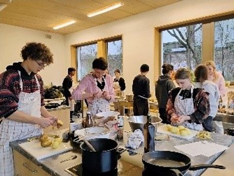 Jugendliche schälen an mehreren Kochinseln Kartoffeln