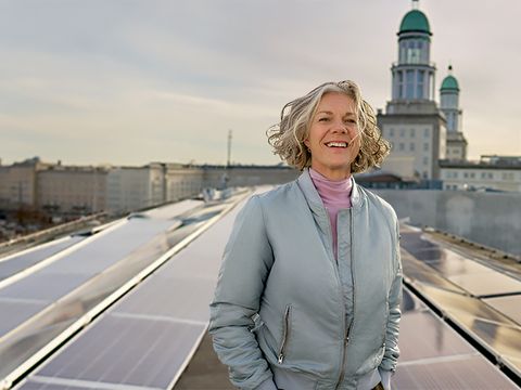 Frau auf Dach in der Petersburger Strasse. Im Hintergrund Solarpanel und die Skyline von Berlin.