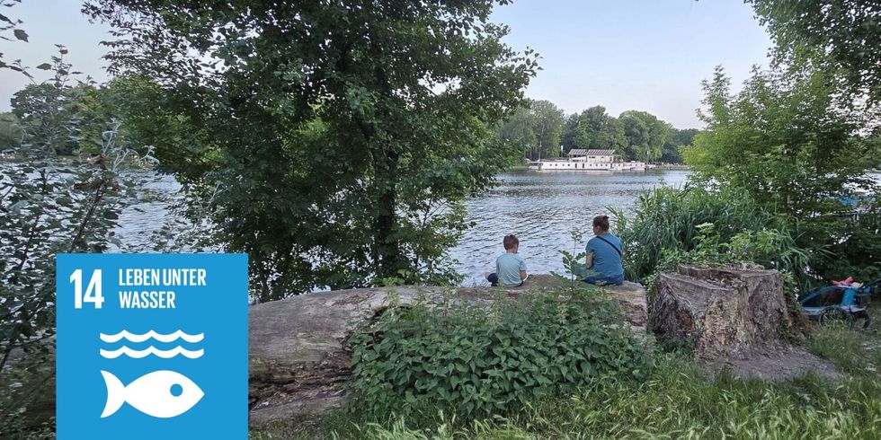 Personen sitzen am Wasser an der Spree