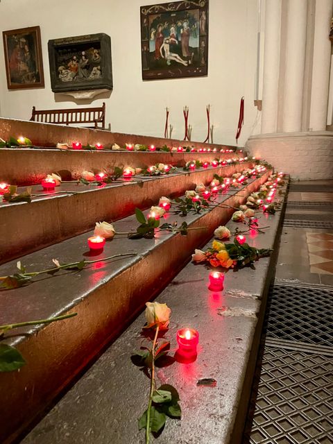 Rosen und Kerzen auf einer Treppe in einer Kirche