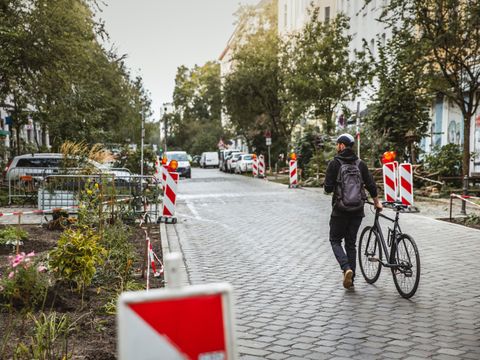 Person schiebt sein Fahrrad auf einer Kopfsteinpflasterstraße