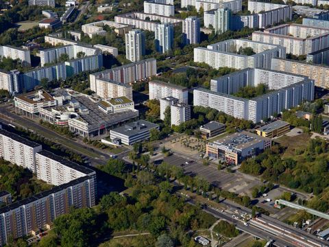 Luftbild mit Plattenbau-Quadraten, Parkplätzen, Einkaufszentrum, Grün