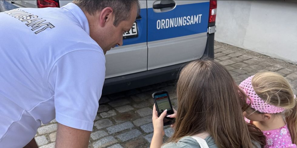 Ein Mitarbeiter des Ordnungsamts erklärt auf dem Blaulichtfest Mutter und Tochter digitale Angebote