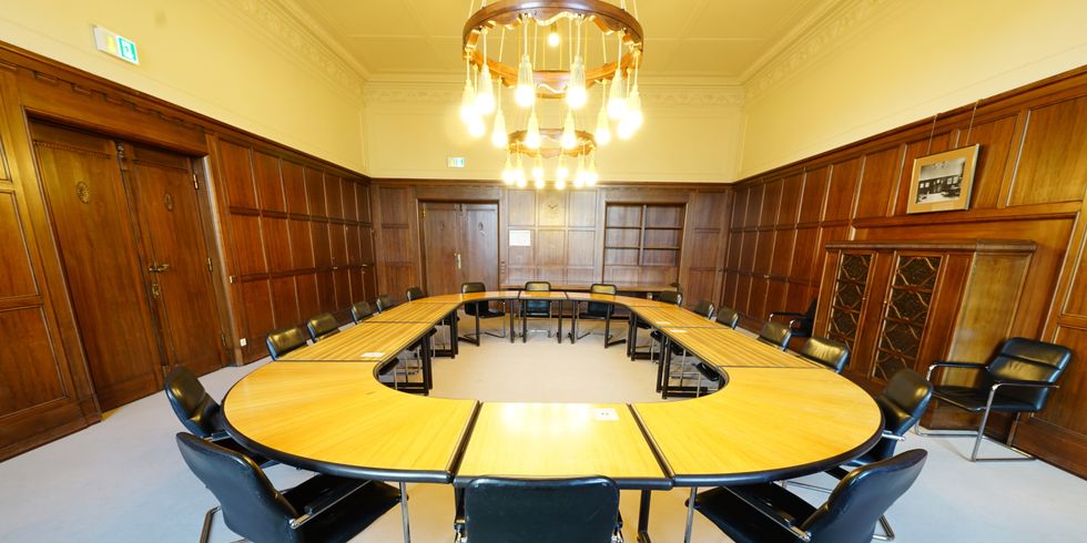 Saalit mit rundem O-Tisch und holzverkleideten Wänden