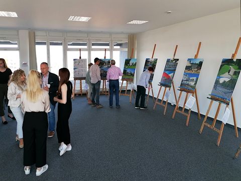 Menschen in einer Ausstellung mit Vorher-Nachher-Bildern auf Staffeleien