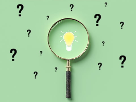 A magnifying glass in the centre of the picture, a light bulb under the glass, several question marks in the background.