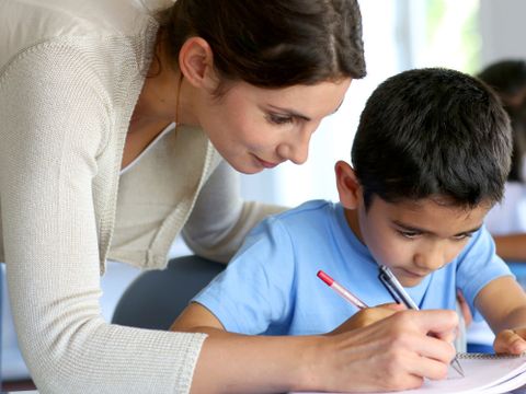 Lehrerin hilft kleinem Jungen bei den Hausaufgaben
