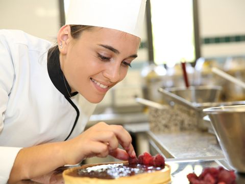 Fröhliches Mädchen in der Lehrküche, die Kuchen macht