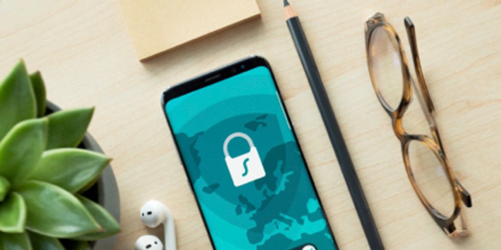 Handy, Kopfhörer, Brille, Stift und Topfplanze liegen auf einem Tisch