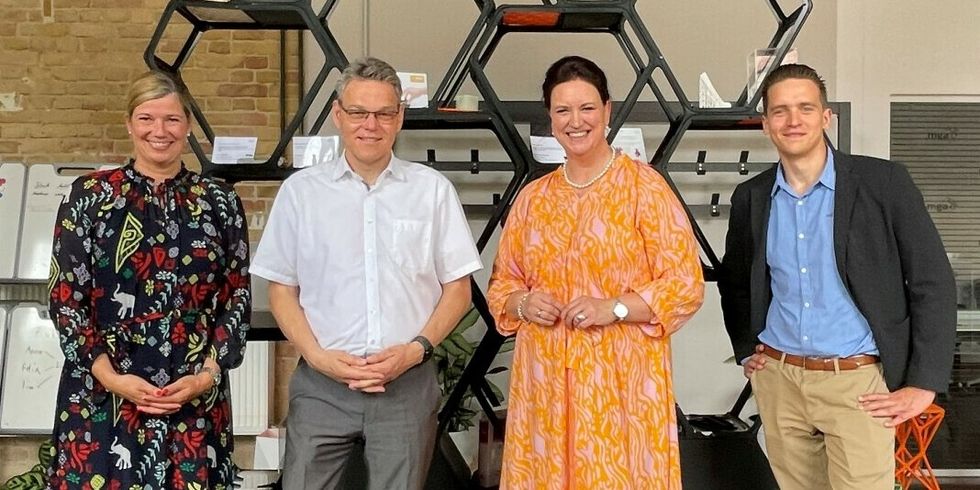 Vier Personen stehen nebeneinander und lächeln.