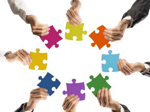 Hände mit Puzzleteilen bilden einen Kreis
