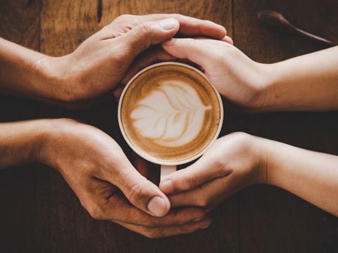 Einte Tasse Kaffee in den Händen eines Mannes und einer Frau.
