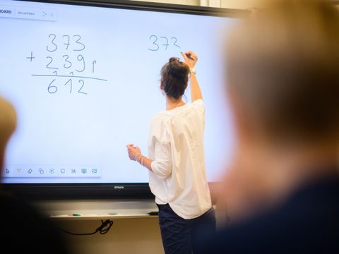 Lehrkraft schreibt auf Smartboard