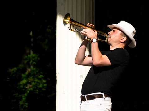 Ein Trompeter spielt sein Instrument, während er von der Sonne angestrahlt wird