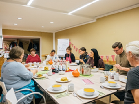 mehrere Personen sitzen zusammen an einem großen gedeckten Tisch