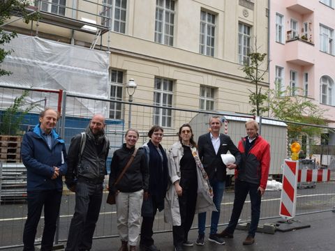 Bezirksstadtrat Ephraim Gothe (r.) und ein Team aus FM, Planungsbüro und Baufirma vor der Baustelle des Volkshochschulgebäudes in der Antonstraße