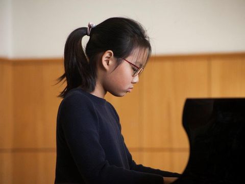 Junges Mädchen spielt am Flügel