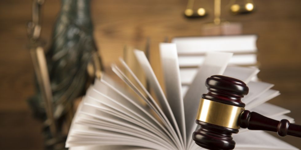 Justitia, hölzener Richterhammer und ein aufgeschlagenes Buch