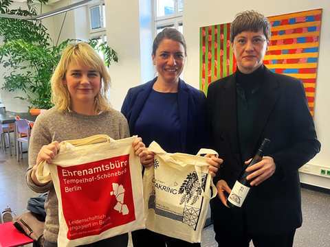 Drei Personen lächeln in die Kamera