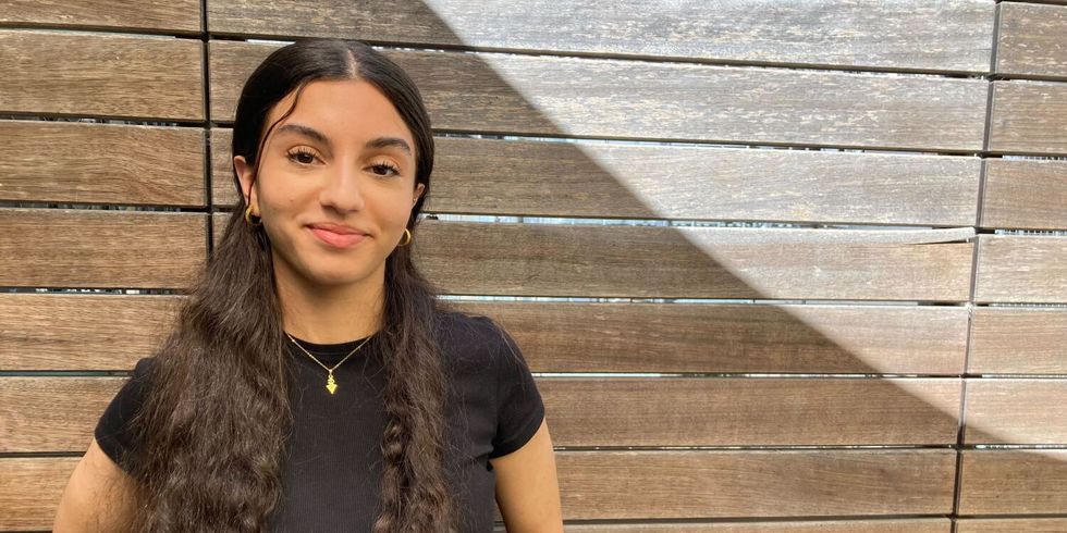 Aziza Egla vor Holzwand