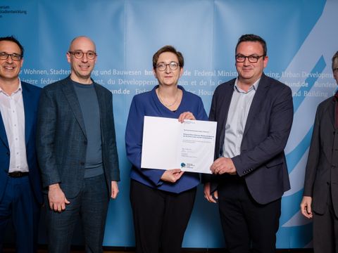 Bundesbauministerin Klara Geywitz übergibt im Rahmen einer feierlichen Zeremonie eine Urkunde an Bezirksstadtrat Urban Aykal. (Bild: Henning Schacht)