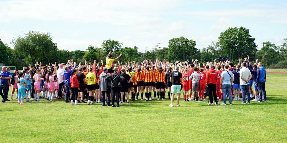 Auf einem Sportplatz stehen viele Sportteams in unterschiedlichen Trikots.
