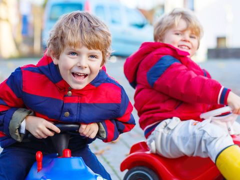 Two little kids boys playing with toy cars, outdoors