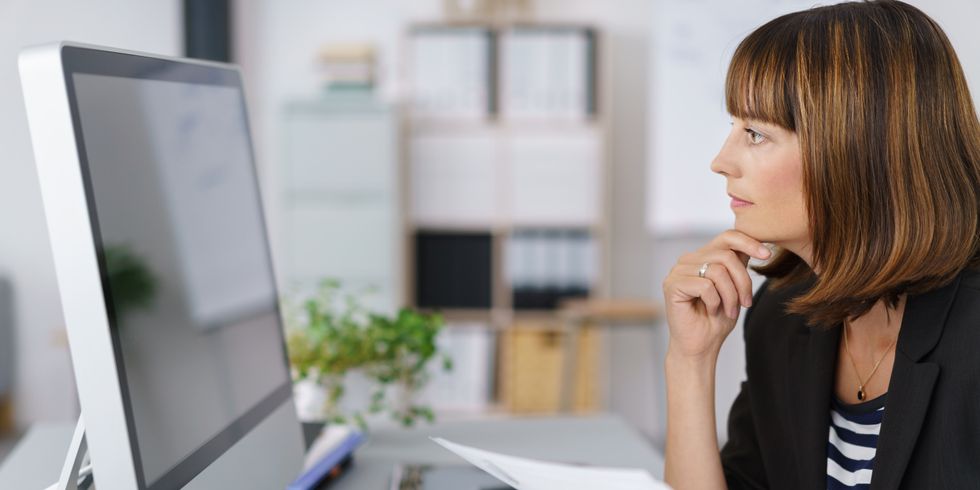 Frau sitzt mit Formular vor dem PC