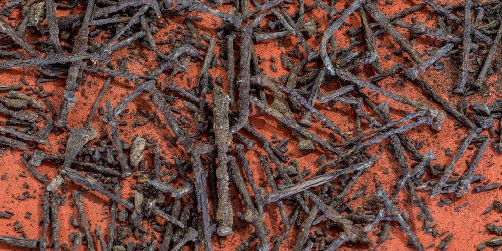 viele verrostete Nägel liegen auf rotem Sand