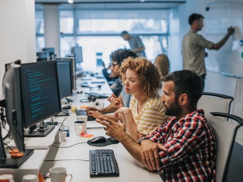 Mehrere Menschen sitzen in einem Büro vor Computern