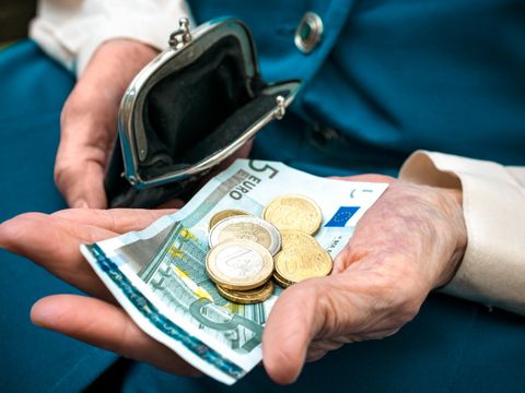Seniorenhände halten Geld und ein Portemonnaie