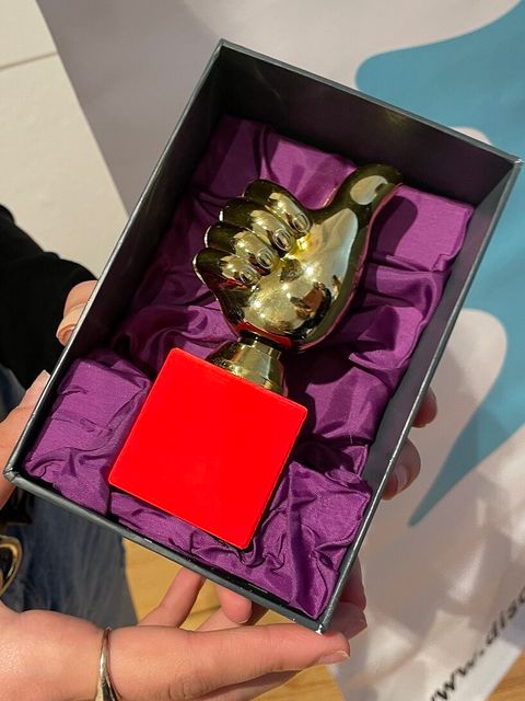 Eine goldener Pokal in Form einer Hand, die den Daumen nach oben zeigt, liegt in einer Schatulle.