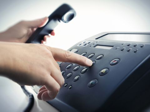 Eine Hand wählt eine Rufnummer auf dem Telefon