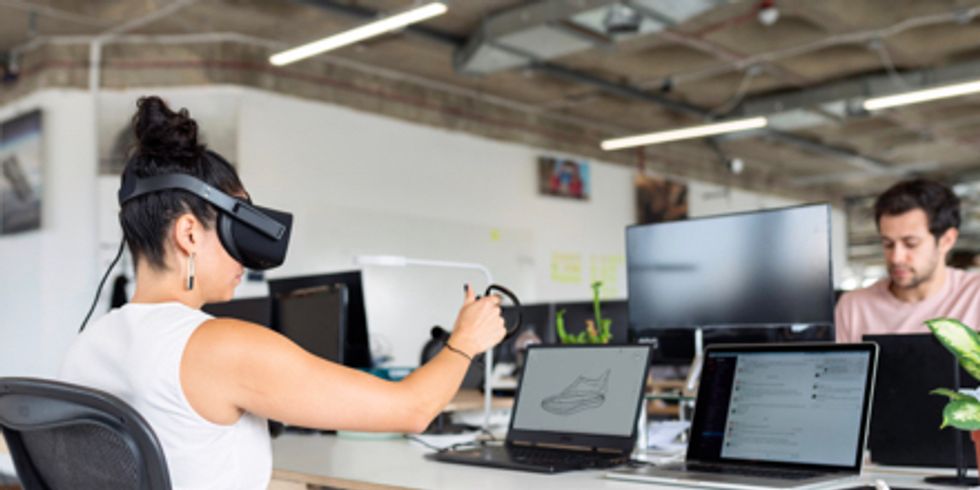 Frau mit VR-Brille vor Laptop, ihr gegenüber sitzt ein Mann