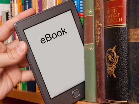 eBook vs Buch, e-Reader aus einem Bücherregal ziehen