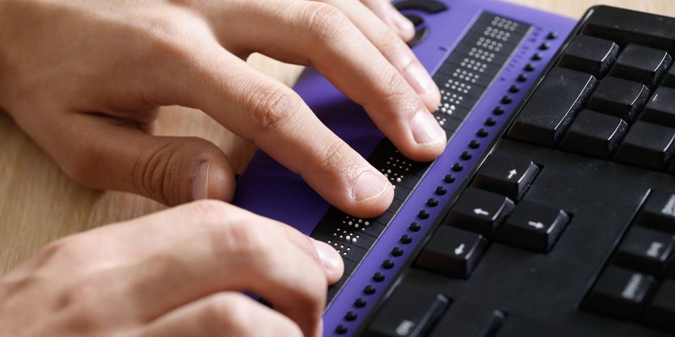 Hände, die eine Braillezeile an der Computertastatur verwenden