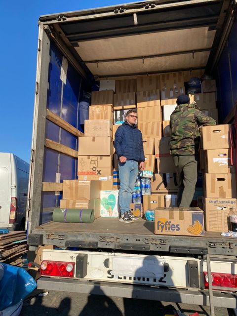 Zwei Männer stehen auf der Laderampe eines LKW und sortieren Kisten.