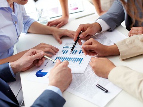 Mehrere Personen besprechen auf einem Tisch liegende Diagramme