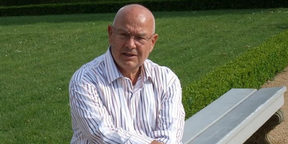 Lothar Voigtlaender sitzt vor einer grünen Wiese auf einer Parkbank