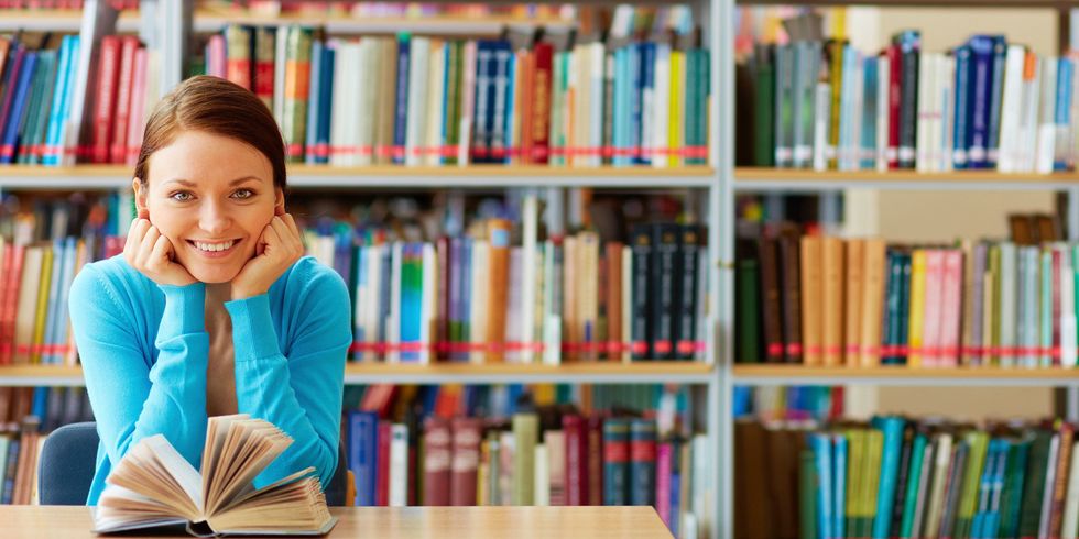 Junge Frau mit vielen Büchern im Hintergrund