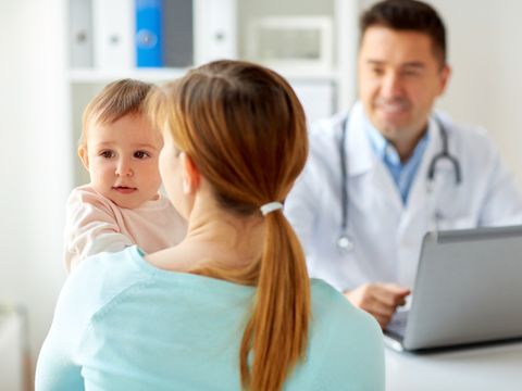 woman with baby and doctor with laptop at clinic