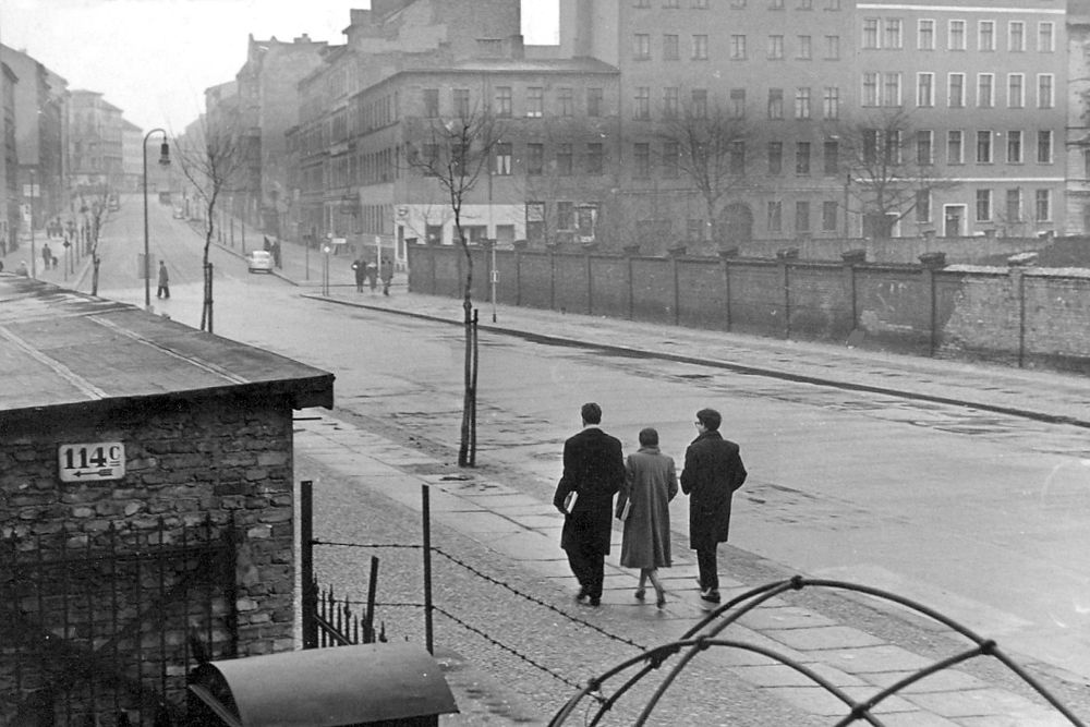 Blick von der Bernauer Straße Nr. 114 auf die Kreuzung mit der Ackerstraße und rechts auf die Friedhofsmauer der Sophiengemeinde, 1959. Der Gebäudebestand an der Bernauer Straße war hier in großen Teilen erhalten geblieben. (Bild: Stiftung Berliner Mauer / Privatarchiv Jörg Hildebrandt)