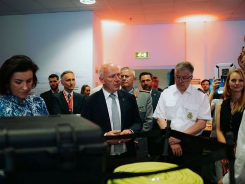 Ansicht Feuerwehrequipment und Kai Wegner und Teilnehmende, die einem Vortrag zuhören