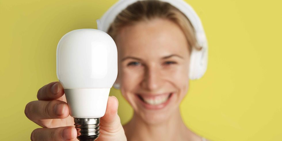 Blonde Frau hält Glühlampe in der Hand.