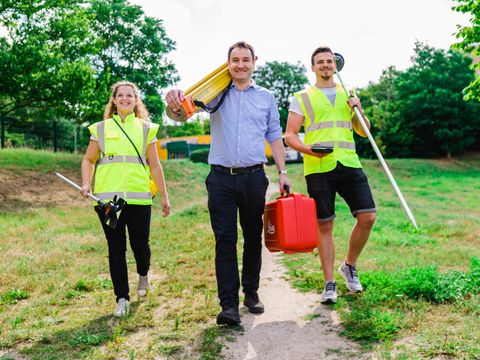 Team Vermessungstechniker laufen lachend einen Weg entlang