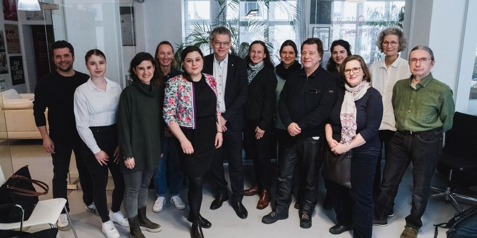 Eine Gruppe Menschen steht zusammen in einer Halle und posiert für ein Foto.