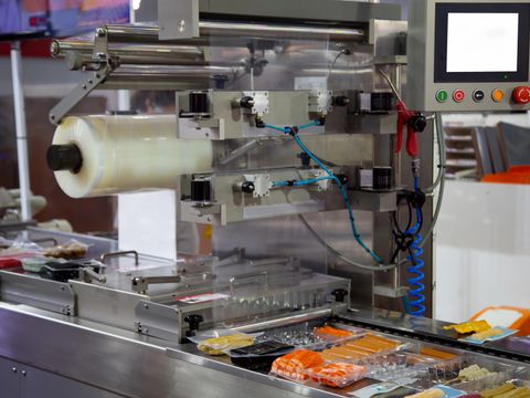 Verarbeitung der Verpackung von Fleischbällchen und Würstchen auf einer Vakuumverpackungsmaschine in einer Lebensmittelindustrieanlage