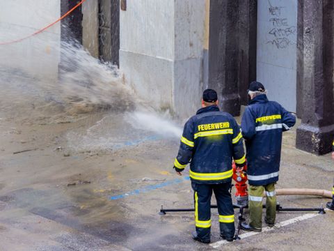 Zwei Feuerwehrmänner pumpem Wasser im Hochwassergebiet ab