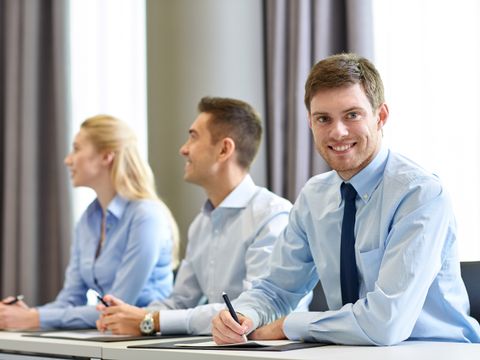 Drei lächelnde Geschäftsleute sitzen im Büro