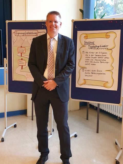 Jugendstadtrat Tobias Dollase (parteilos für CDU) vor Steckbrief Tagespflege (Bild: BA Reinickendorf)